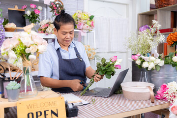 Asian, small business, flower, shop, lifestyle florist decorating bouquet with scissors, LGBTQ woman managing blooming business in modern cozy workspace, middle-aged entrepreneur running flower store