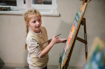 Girl enjoys painting in workshop. Art lesson. Education and learning concept. Child draw a picture...