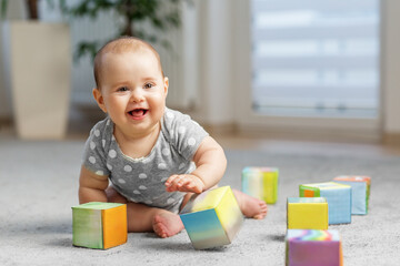 Smiling baby playing with colorful blocks