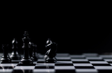 Queen chess piece stands among fallen silver knights, rooks, bishops and pawns on a chessboard....