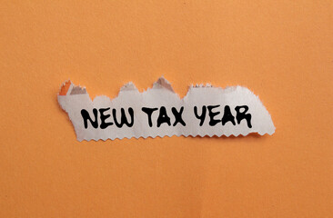New tax year message written on ripped torn newspaper piece on orange background. Conceptual new...