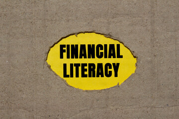 Financial literacy message written on ripped torn cardboard paper on yellow background. Conceptual...