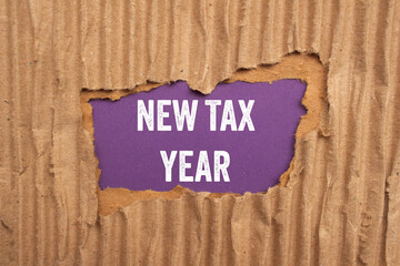 New tax year message written on ripped torn cardboard paper on purple background. Conceptual new...