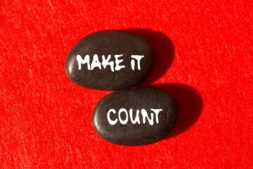 Make it count message written on black stones on red background. Conceptual make it count symbol. Copy space.