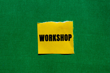 Workshop message written on ripped torn yellow paper piece on green background. Conceptual Workshop...