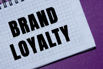 Brand loyalty message written on notebook page on purple background. Conceptual brand loyalty...