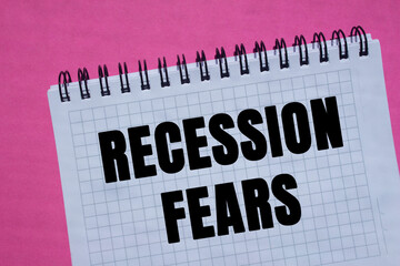 Recession fears message written on notebook page on pink background. Conceptual recession fears...