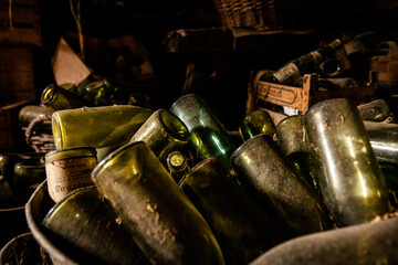 Close-up of dusty old glass bottles in an abandoned rustic farmhouse cellar with warm natural light