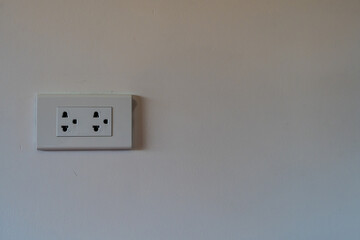 Modern double electrical power socket plug outlet on white concrete wall background with copy space.
