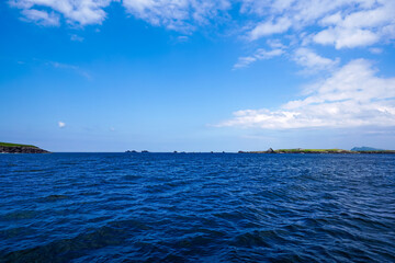 View of the deep blue Atlantic Ocean with distant green coastal rocks and islands