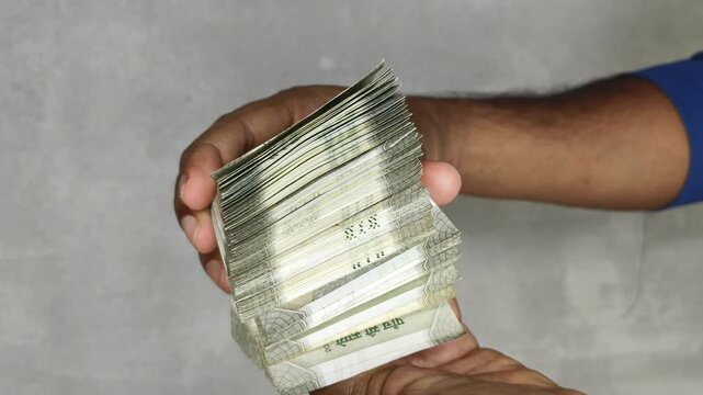 Extreme close up of hand showing and flipping stack of 500 rupees Indian currency notes. Budget, savings, black money, profit, illegal income, wealth, success, corruption and bribery concept.