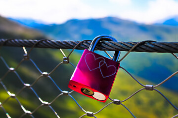 Love lock on mountain bridge fence
A bright pink padlock with two intertwined hearts engraved on it...