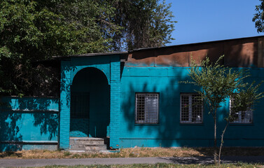 An old blue brick building on a sunny day with shadows