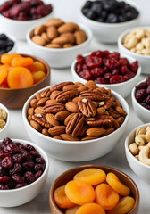 Table is covered with a variety of bowls filled with nuts and dried fruit. The bowls are arranged in a way that creates a visually appealing display. The center bowl is filled with nuts