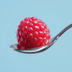 Fresh raspberry sitting on a spoon against light blue background