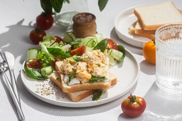 Scrambled eggs on toast bread with cucumber, tomato and herbs.White background.Healthy breakfast
