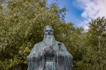 A statue of Confucius stands majestically in the serene Huamin Chinese Park in Moscow, surrounded...