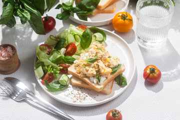 Scrambled eggs on toast bread with cucumber, tomato and herbs.White background.Healthy breakfast