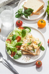 Scrambled eggs on toast bread with cucumber, tomato and herbs.White background.Healthy breakfast