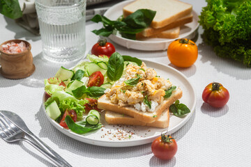 Scrambled eggs on toast bread with cucumber, tomato and herbs.White background.Healthy breakfast