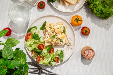 Scrambled eggs on toast bread with cucumber, tomato and herbs.White background.Healthy breakfast
