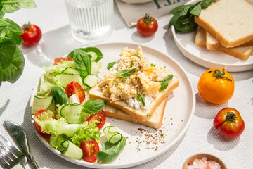 Scrambled eggs on toast bread with cucumber, tomato and herbs.White background.Healthy breakfast