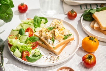 Scrambled eggs on toast bread with cucumber, tomato and herbs.White background.Healthy breakfast