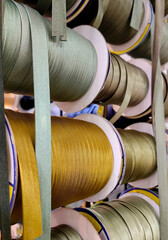 coils bias tape in various colors are neatly organized on racks in textile processing workshop,...