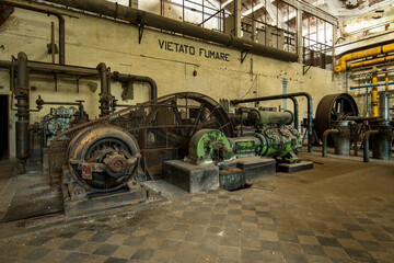 Rusty abandoned industrial machinery in a decaying factory with vintage pipes and worn tiled floor