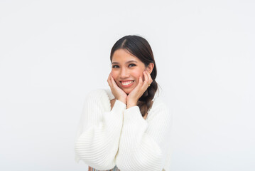 Charming Southeast Asian lady beams brightly with expressive eyes and hands under her chin. Joyful, sweet, and friendly with cozy white fashion in white background.
