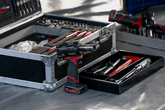 Professional mechanic tool set with cordless drill, socket wrenches, and hand tools organized in a workshop for automotive repair or vehicle maintenance