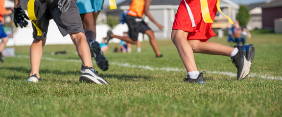 Youth athletes participate in flag football practice on a sunny day in a community park, showcasing teamwork and skill development