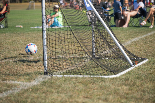 Soccer ball approaching the goal during a youth match on a sunny afternoon in a local park