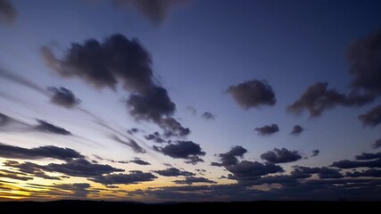 breathtaking timelapse of early dawn sky evolving from deep twilight blue to radiant sunrise with fast moving cloud formations painting the heavens in vibrant hues above tranquil natural scenery