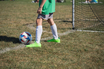 Youth soccer player prepares for corner kick during afternoon match on a grassy field