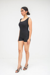 Asian teen model poses in a black one-piece with confident expression. Right-angle full-body pose...