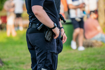 Police officer on duty wearing tactical uniform with visible firearm holstered during public...