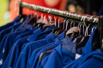 Fototapeta premium Blue sportswear hoodies on clothes rack at outdoor retail stall during event or festival with hangers and blurred background