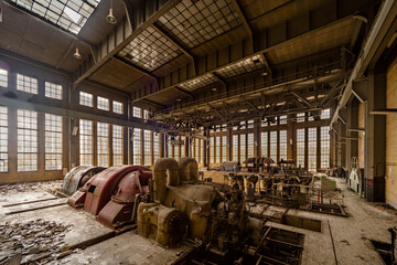 Interior view of an abandoned industrial power plant with large machinery and natural light...