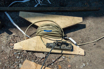 A power extension cord is neatly coiled and placed on a wooden board in a construction area,...