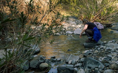 Hiker woman refreshing in a mountain stream during hiking trip