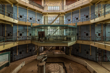 Abandoned octagonal industrial control room with glass office and multi-level staircases in a derelict French winery