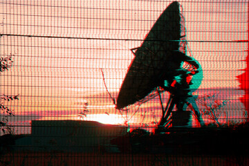 Dish receiver for satellite communications silhouetted by a sunset. With a warped dystopian infrared edit