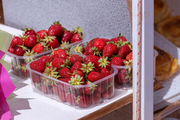 Red strawberries in plastic transparent box. Fresh juicy berry harvest for healthy snack and dessert. Farmers market produce.