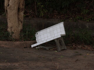 A weathered bench on a neglected sidewalk, highlighting themes of abandonment and decay