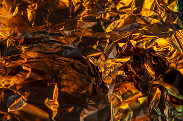 A close-up shot of crumpled aluminum foil, illuminated with warm, golden light, creating a textured...