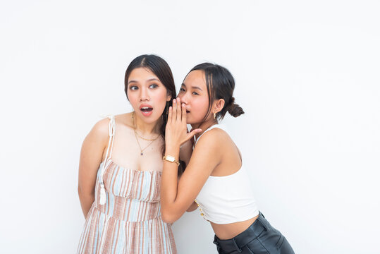 A Stunned young Asian Women while listening to her friend's scandalous and shocking gossip. Isolated on a white background.