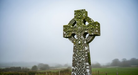 Celtic Cross in Misty Field - Ancient Celtic cross stands tall in a misty field, showcasing intricate carvings and weathered stone. Tranquil and serene