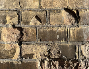 Weathered beige-brown brick wall with rough, rustic texture. Ideal for backgrounds, architecture,...