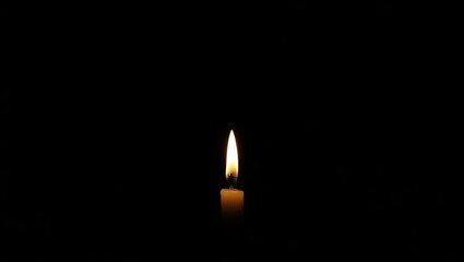 A single candle flame burning brightly in the darkness creating a warm and inviting glow in the night
